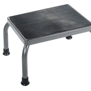 A small, metal step stool with a black non-slip surface and four sturdy legs equipped with rubber feet for stability. The stool is designed to provide a safe and elevated platform.