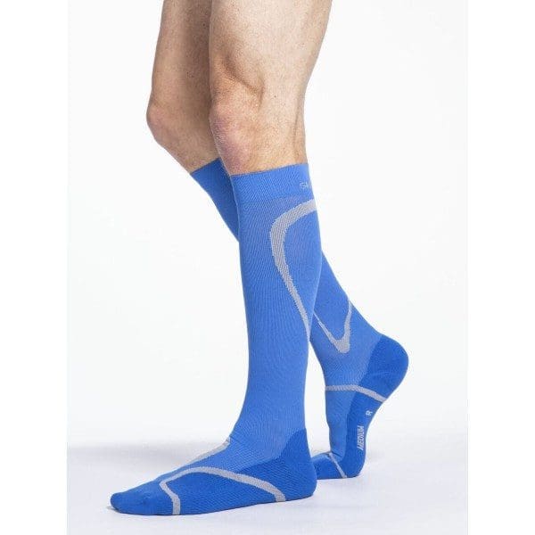 A person wearing blue knee-high compression socks with lighter blue accents stands on a white background.