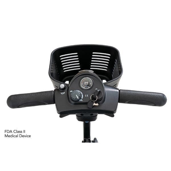 Close-up of a scooter handlebar with a storage basket. Features include a power switch, speed control dial, and key ignition. The label on the side reads FDA Class II Medical Device.