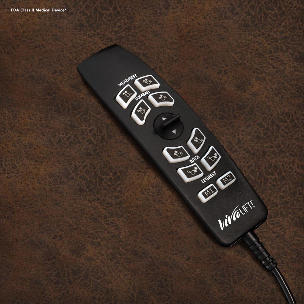 A black remote control with buttons for adjusting the headrest, lumbar, back, and legs comes with the Pride VivaLift! Tranquil 2 PLR-935 Recliner. It includes M1 and M2 shortcuts, has a Viva Lift logo, and sits on a brown textured surface.