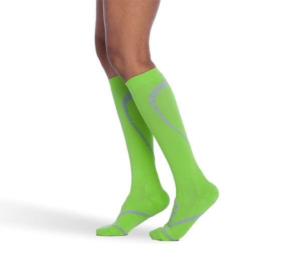 A person wearing bright green knee-high socks with gray patterns.