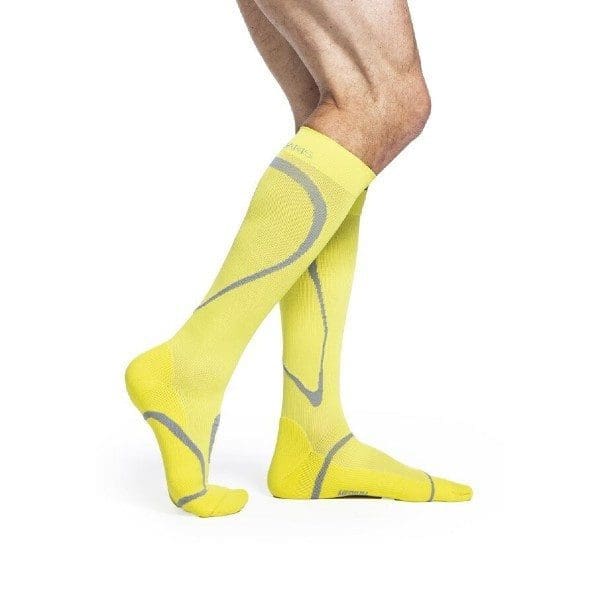 A person wearing bright yellow knee-high compression socks with gray accent lines. The socks cover the calves and feet, showcasing a sleek and fitted design ideal for athletic or supportive use.