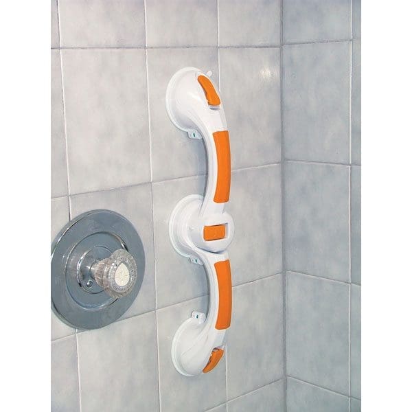 A shower grab bar with white and orange accents is attached to a tiled wall next to a metal faucet. The tiles are light gray, and the grab bar is secured with large suction cups.