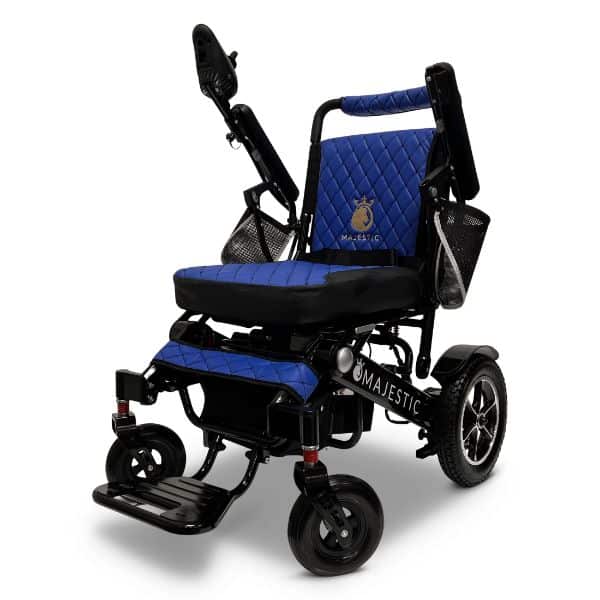 The MAJESTIC IQ-7000 electric wheelchair features a blue and black design with quilted seat and backrest. It includes armrests, footrests, two front wheels for maneuverability, and a sleek black frame displaying the Majestic logo on the side.