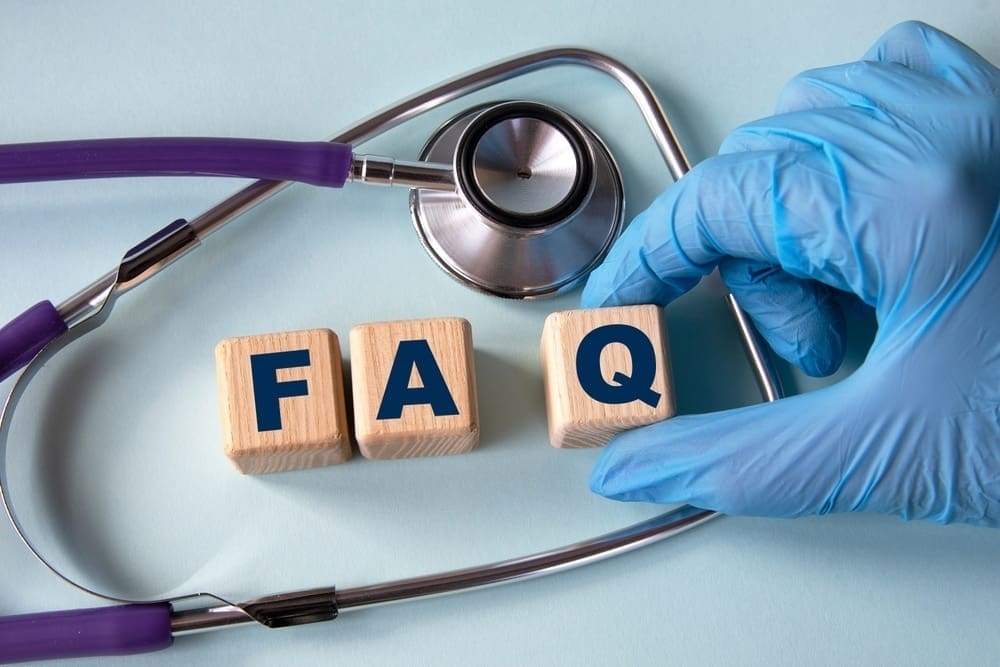 A stethoscope and wooden blocks spelling FAQ are arranged on a light blue surface, evoking a touch of Nashville charm. A gloved hand holds one of the blocks, hinting at insights into medical equipment practices.