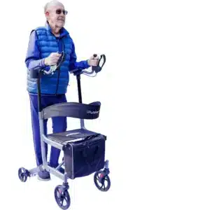 An elderly man in sunglasses and a blue vest uses an UPWalker® EZ Lite, a tool-free, folding Backsaver Rollator with four wheels, a seat, and a small storage bag. The bright white background highlights the man and his stylish mobility aid.