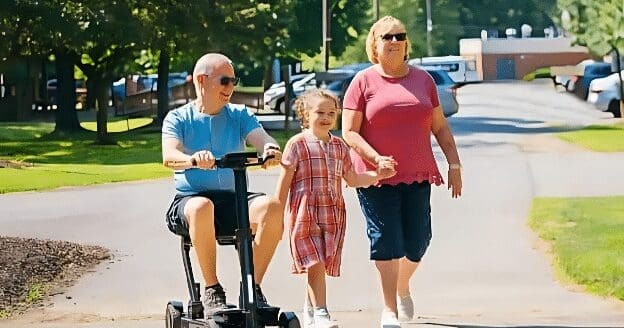 A man in in a portable scooter travels alongside his daughter and wife