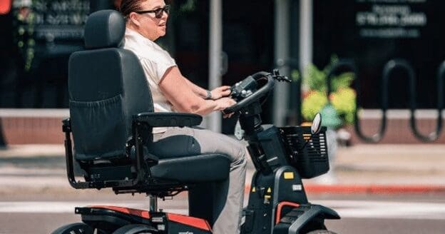 A woman traveling in a black and red mobility scooter